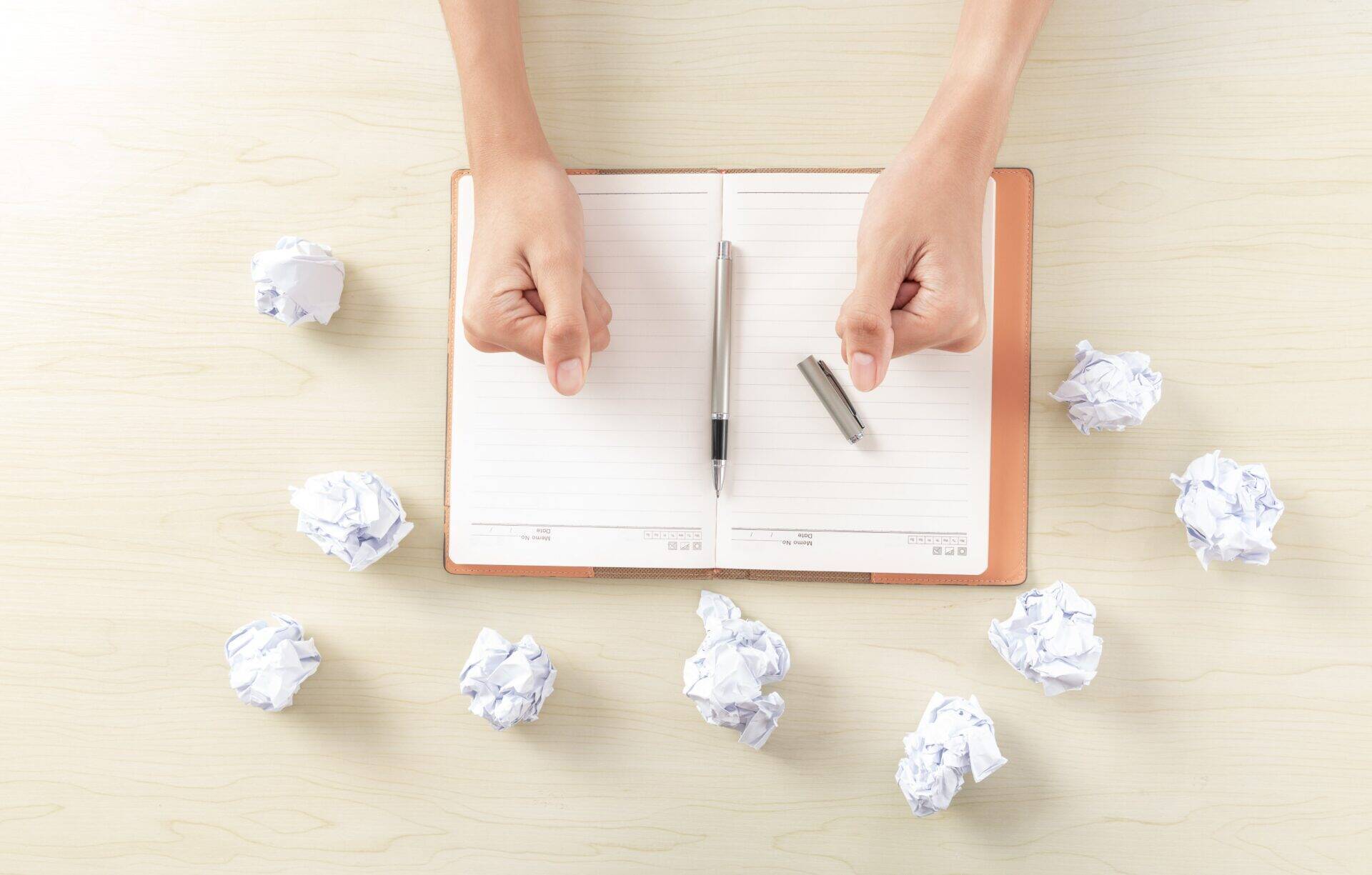 main d'une femme écrivant et froissant des notes en boules de papier